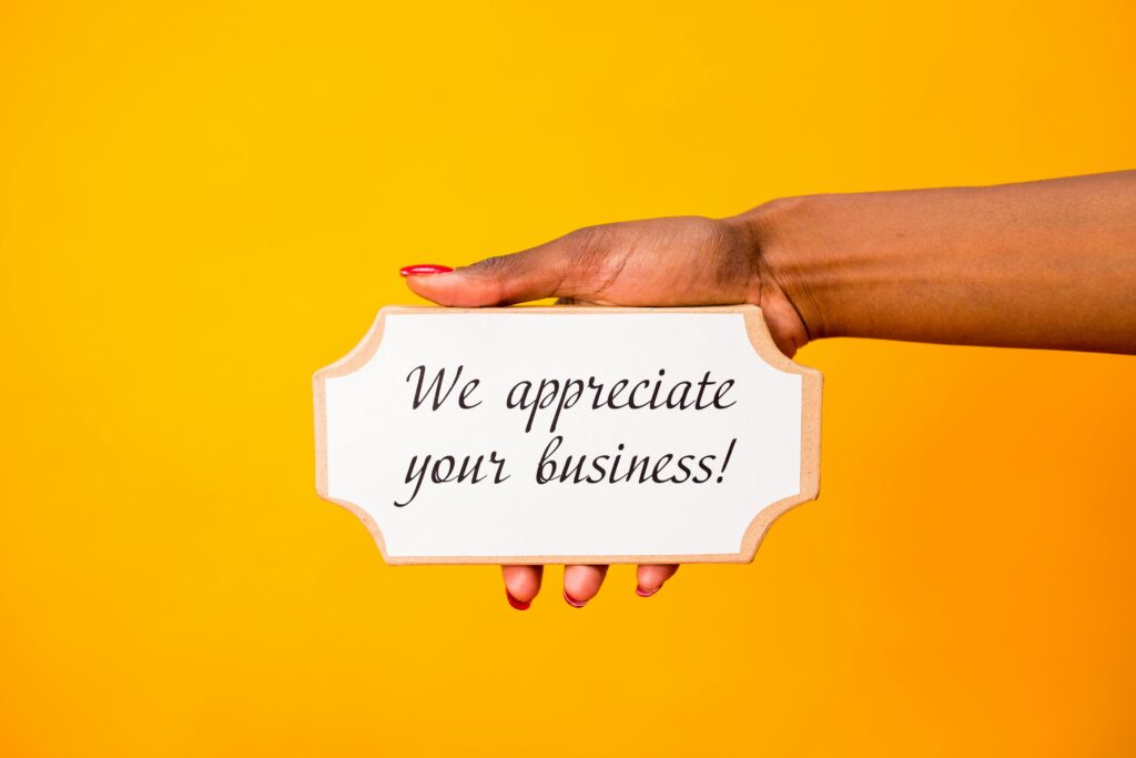 Hand holding a sign that reads: We Appreciate Your Business