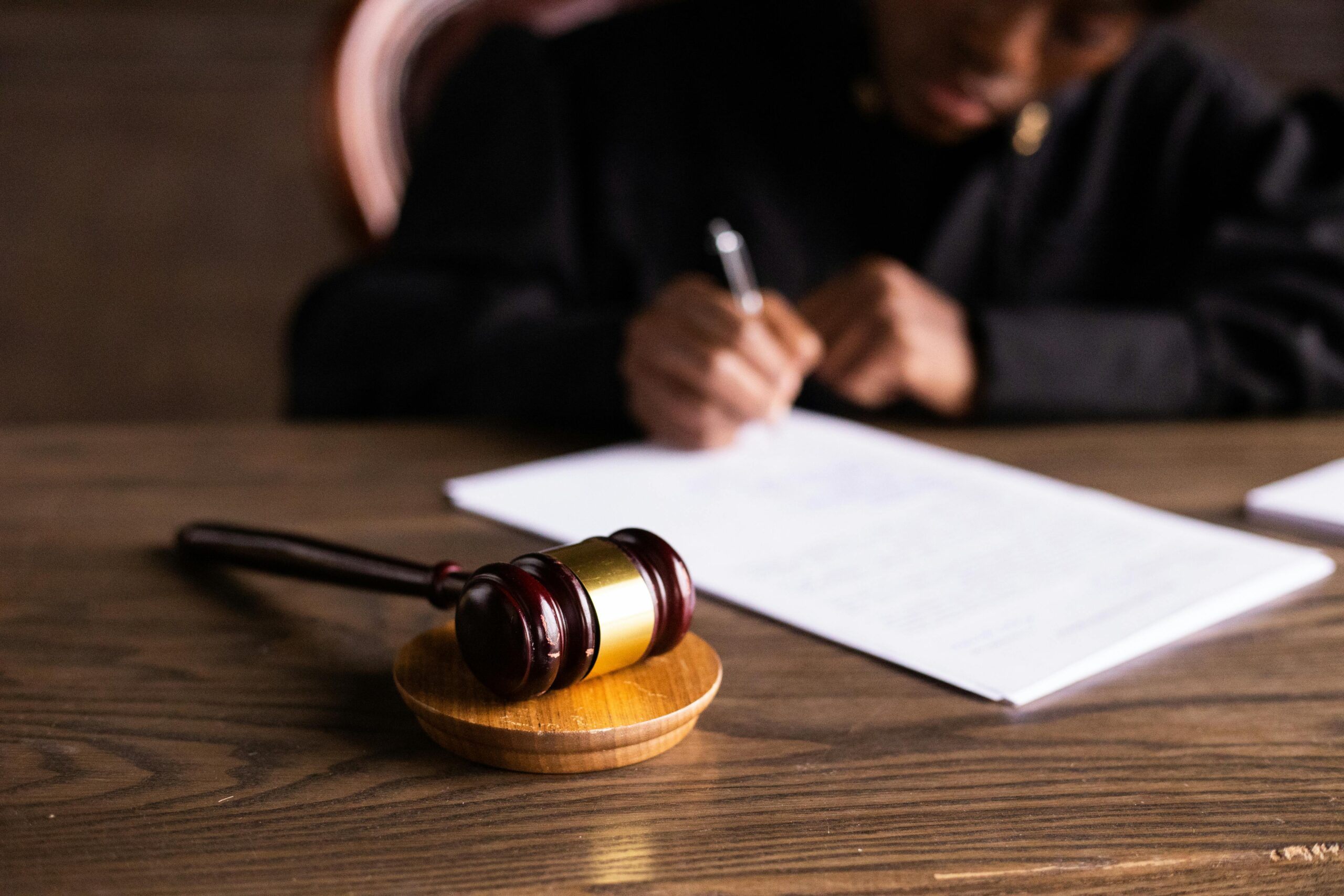 judge in robes signing something at a desk with a gavel