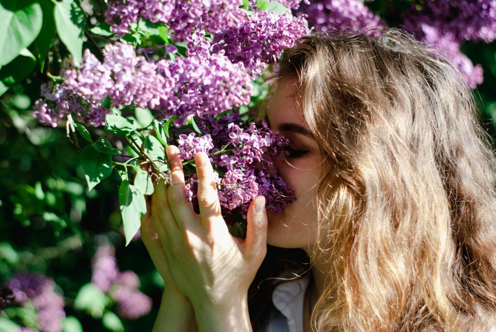 A woman smelling a lilac bush.