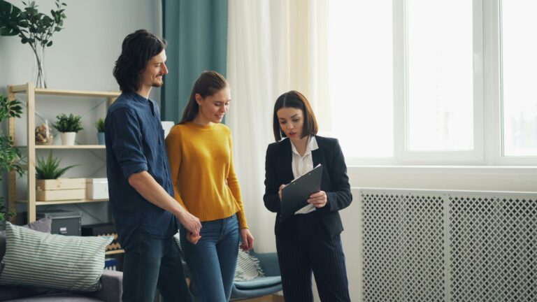 A couple standing with a property manager, who holds a clipboard.