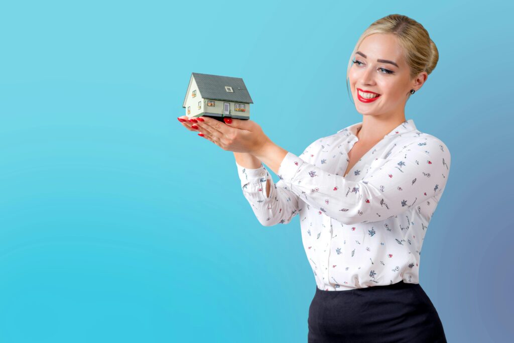 smiling person holding a model house