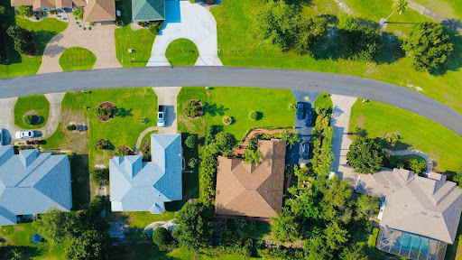 Aerial view of a suburban neighborhood with five houses, green lawns, and a curved road. 