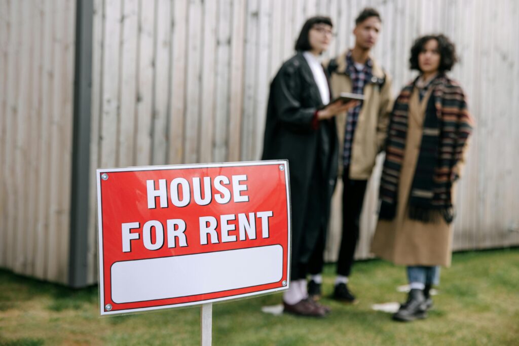 House for Rent sign with Out-of-Focus Agent and Tenants in background