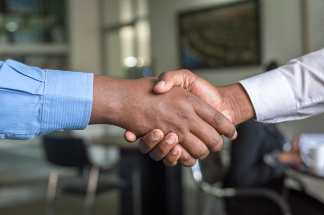 Close-up of two people shaking hands in an office, symbolizing a successful agreement or partnership.