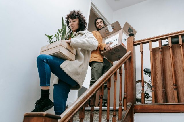 two people carrying moving boxes down stairs